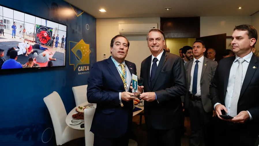 Jair Bolsonaro, então presidente, com Flávio em evento da Caixa, em 10 de maio de 2019. Foto: Isac Nóbrega / PR, via Wikimedia Commons, CC BY 2.0