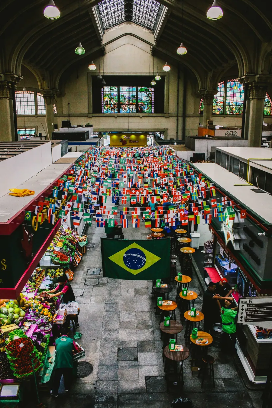 O Mercado Municipal de São Paulo, o Mercadão, visto do alto, com a bandeira do Brasil entre as bancas. Foto: Edilaine Fortunato, CC BY-SA 4.0