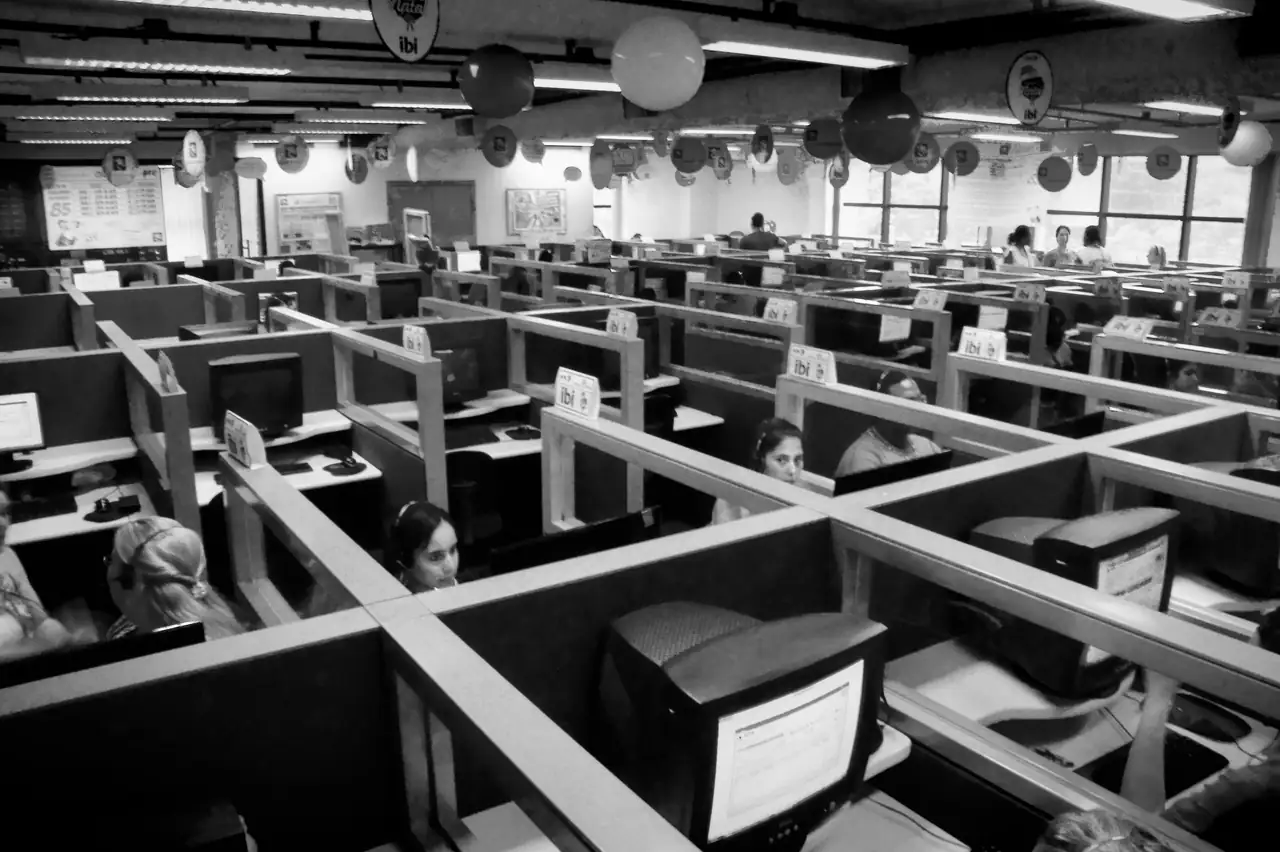 Sala de atendimento com dezenas de computadores e pessoas trabalhando
