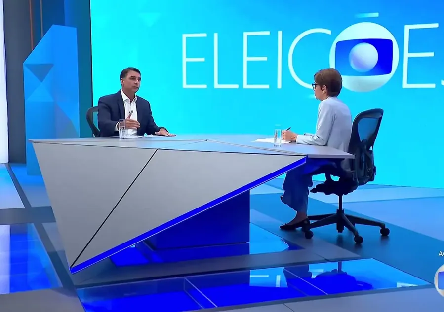 Flávio Bolsonaro e Renata Lo Prete na bancada. Reprodução/TV Globo, 16/10/2026